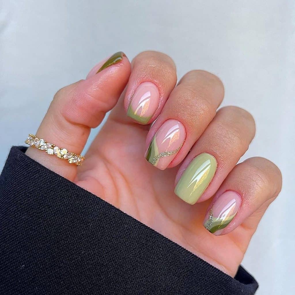 A woman's hand with green and gold nails.