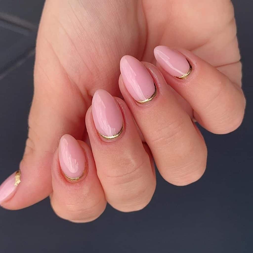 A woman's hand with pink aesthetic nails, each boasting a thin chrome gold reverse French tip
