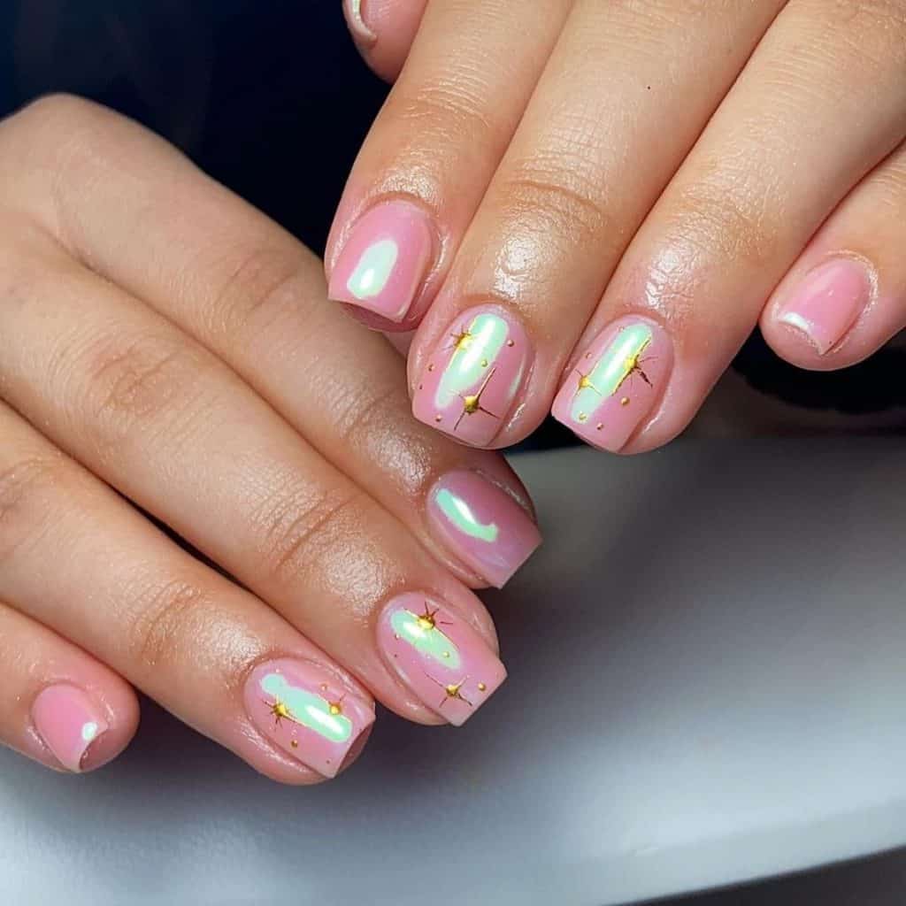A woman's pink and gold chrome nail design, light pink chrome is beautifully accentuated with stars and delicate tiny dots in gold for an opulent finish