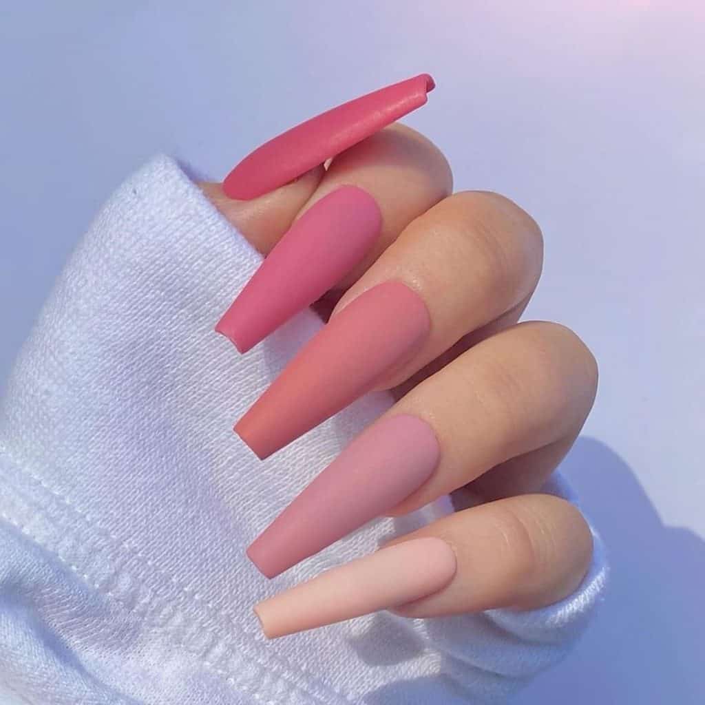 A woman's matter pink nails with a spectrum of pink that softens from thumb to pinky