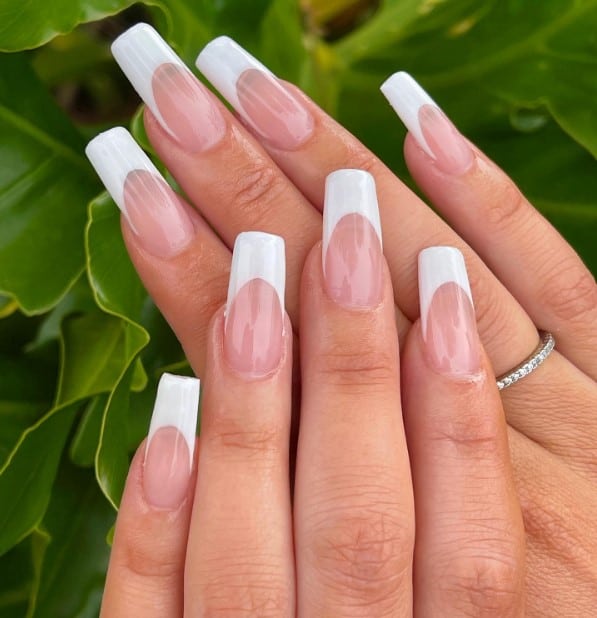 A woman's hands with classic white French tips and a glossy topcoat