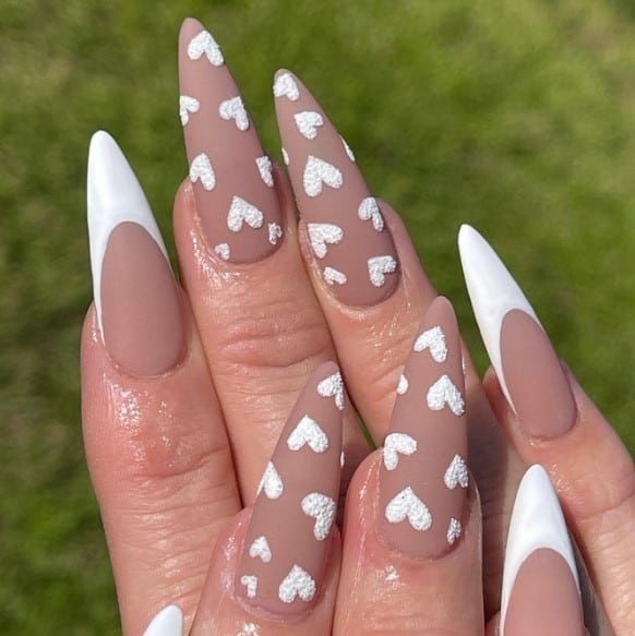 Textured white hearts dance across two nails, while the rest boast chic French tips, blending romance with sophistication in this rose nail design.