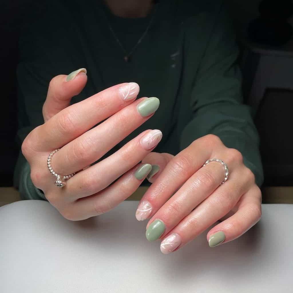 Alternating pastel green nails with clear ones sporting white and green foliage art crafts an elegant aesthetic that's both refreshing and refined.