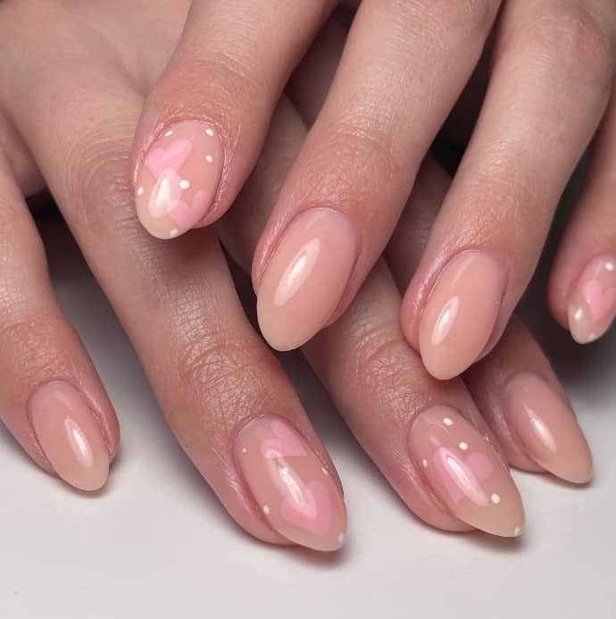 Pinkish nude almond nails flirt with fun in this set, where some nails are adorned sport light pink hearts along with white polka dots