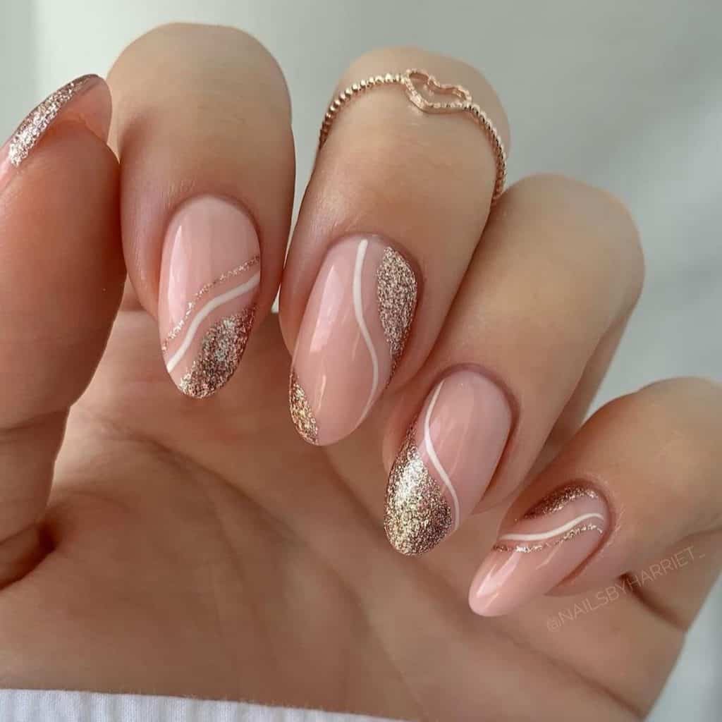 A woman's hand with glossy nude nail is touched by rose gold glitter, painted diagonally either near the tips or the cuticles, framed by a slender outline of white polish