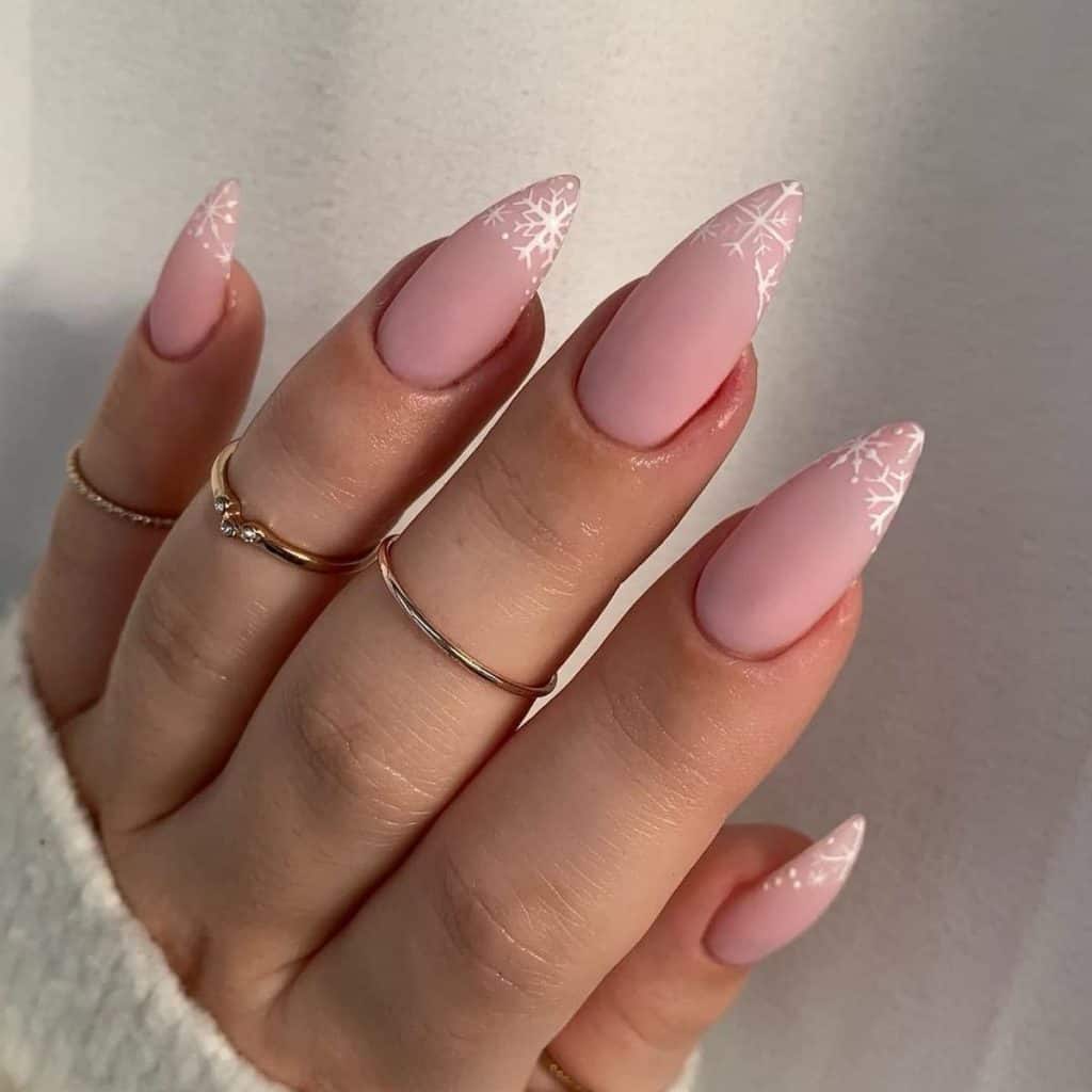 Opt for plain pink nude almond nails, then adorn each tip with intricate snowflake art, giving a wintery twist to the classic French tip.