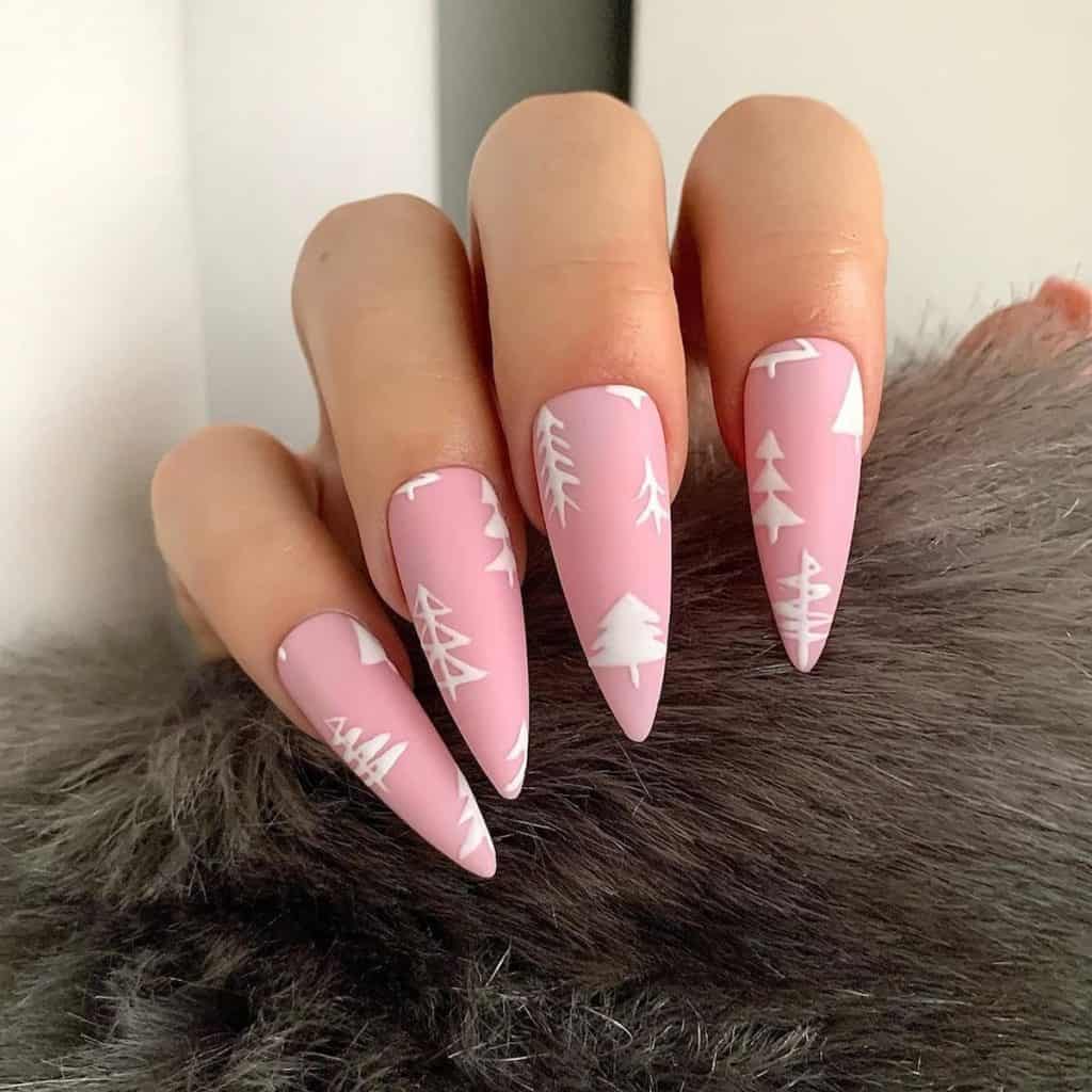A woman's matte blush pink nails in a long almond shape where each one is a delicate forest of white pine tree art