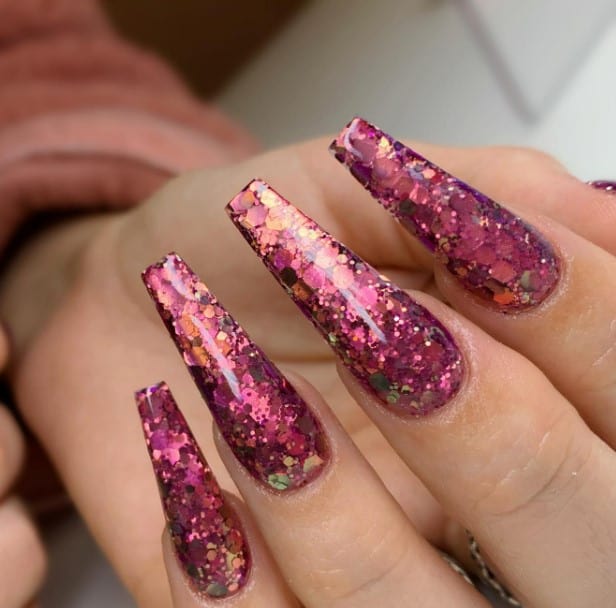 A woman's coffin nails with pink and purple glitter on them.