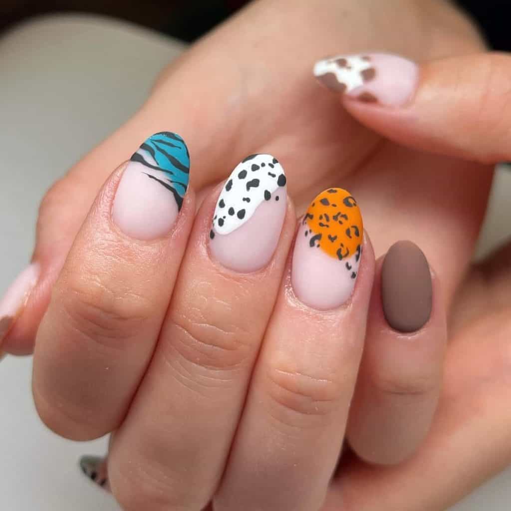 A woman's nails with matte nude nails with tips sporting blue, white, and orange blobs