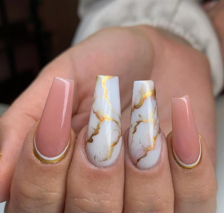 The extra-long nails in the middle are white with golden marbling, and the accent nails are blush pink with reverse tips lined in white and gold for a chic finish.