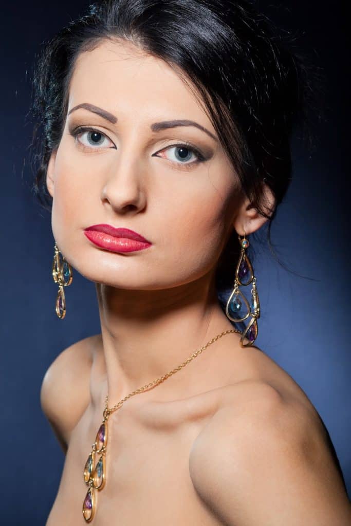 A beautiful elegant woman wearing jewelry and posing for a photo.