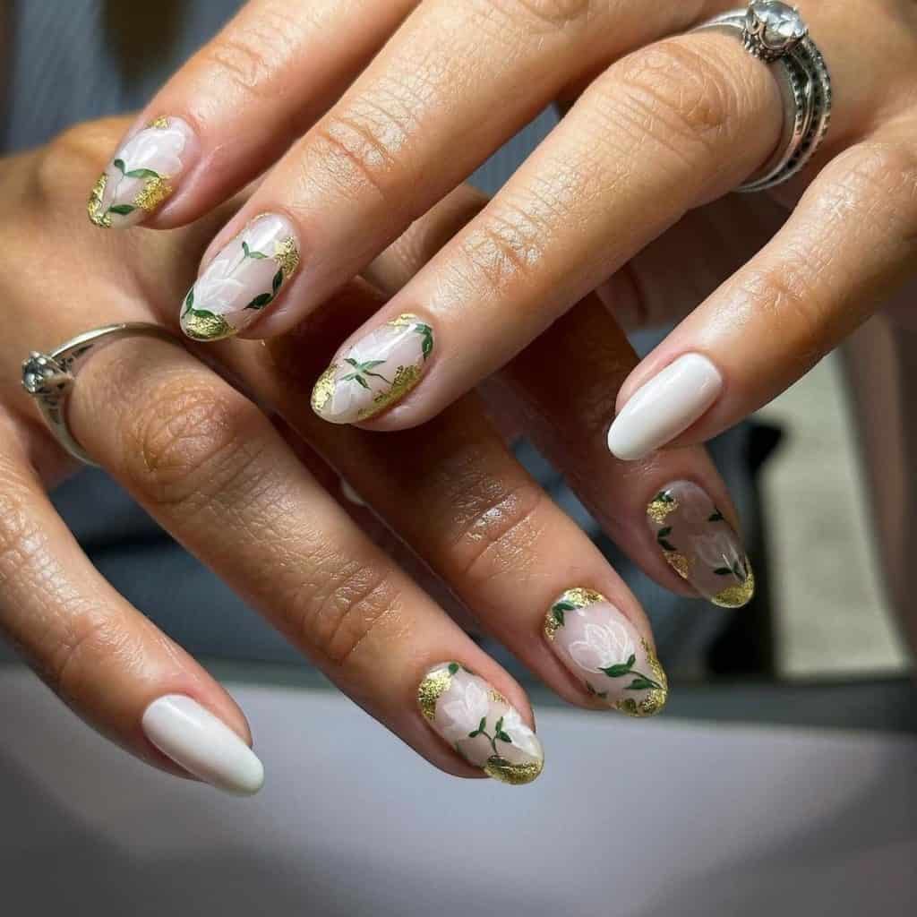 A woman's hands with white nails are adorned with intricate designs of delicate leaves and flowers
