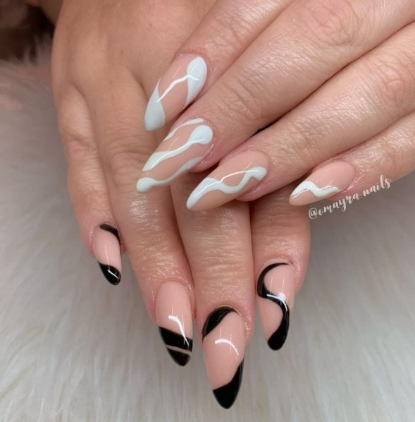 Decorated with squiggly swirls, diagonal tips, and vertical blobs, these peachy nude almond nails play with contrasts using black polish on one hand and white on the other.