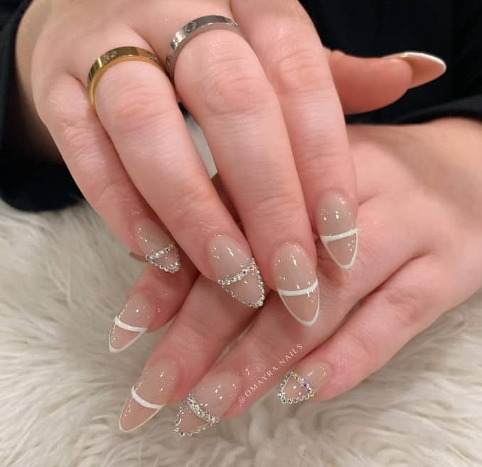 A woman's hands with white nails and a diamond ring.