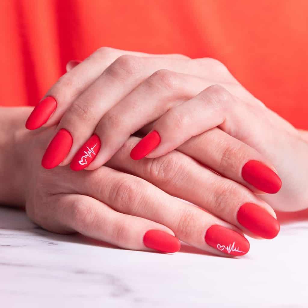 Round matte red nails whisper romance with a minimalist heart outline connected to a heartbeat line in white polish