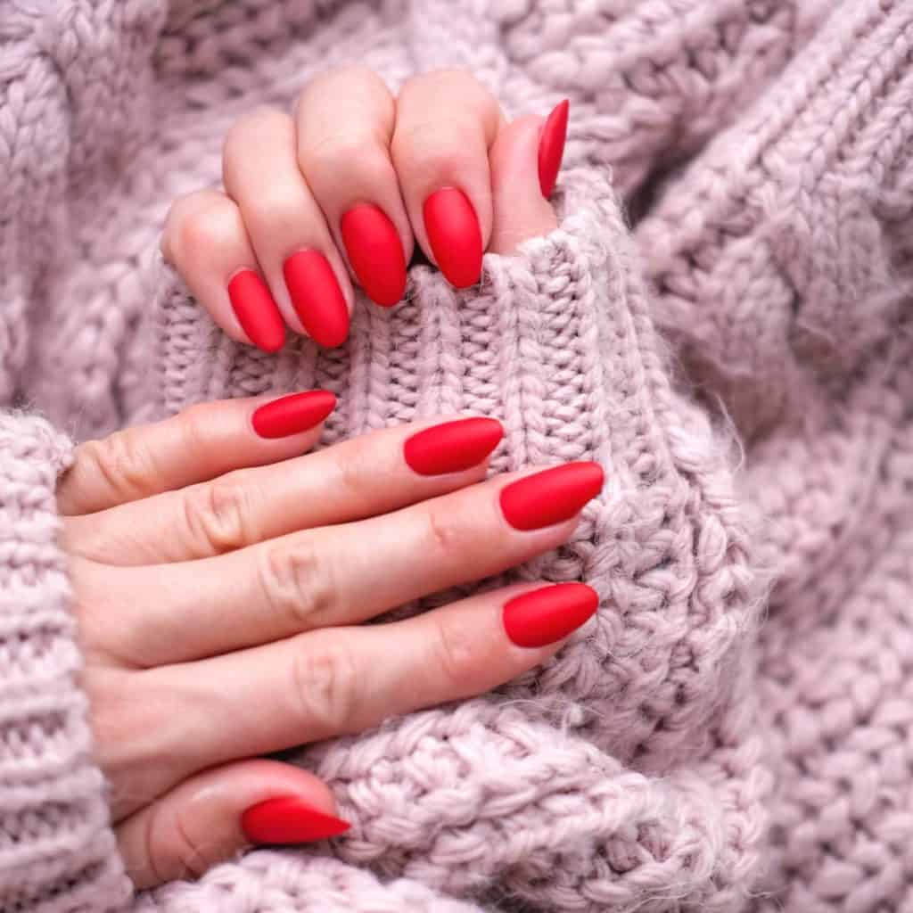 A woman's hands with red nails on a sweater.