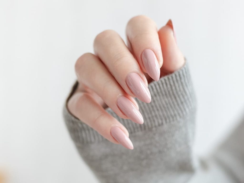 A woman's nails painted in a nude polished with almond shaped nails