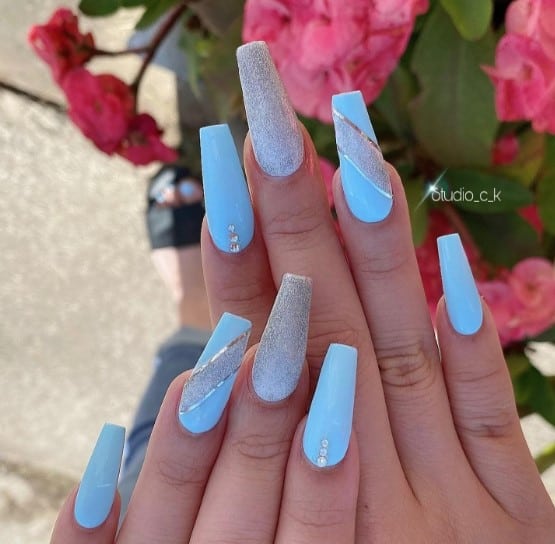 Some nails are adorned with rhinestones near the cuticles, another features nails coated in silver glitter, and another is painted with diagonal silver glitter with chrome silver outlines.