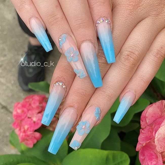 A woman's hand with coffin-shaped blue and white ombre nails.