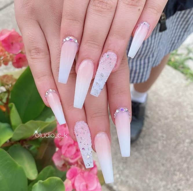 Sheer white and nude pink ombré nails coat each nail where some glisten with rhinestones near the cuticles. 