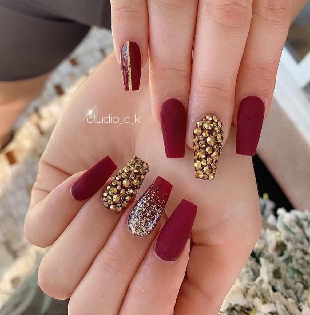 This mani showcases nails encrusted with gold rhinestones, some with an ombré of silver glitter and matte red, and another half glossy and half matte, divided by a striking gold vertical line.