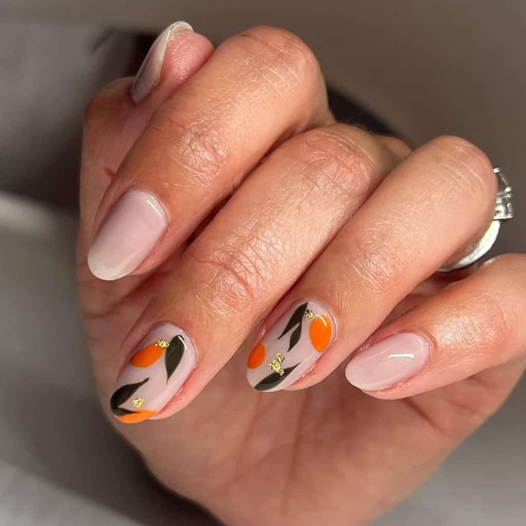 Glossy nude nails set the stage for accent nails that boast dark green leaves and orange blobs reminiscent of an orange grove topped with gold foil for a touch of glitz.
