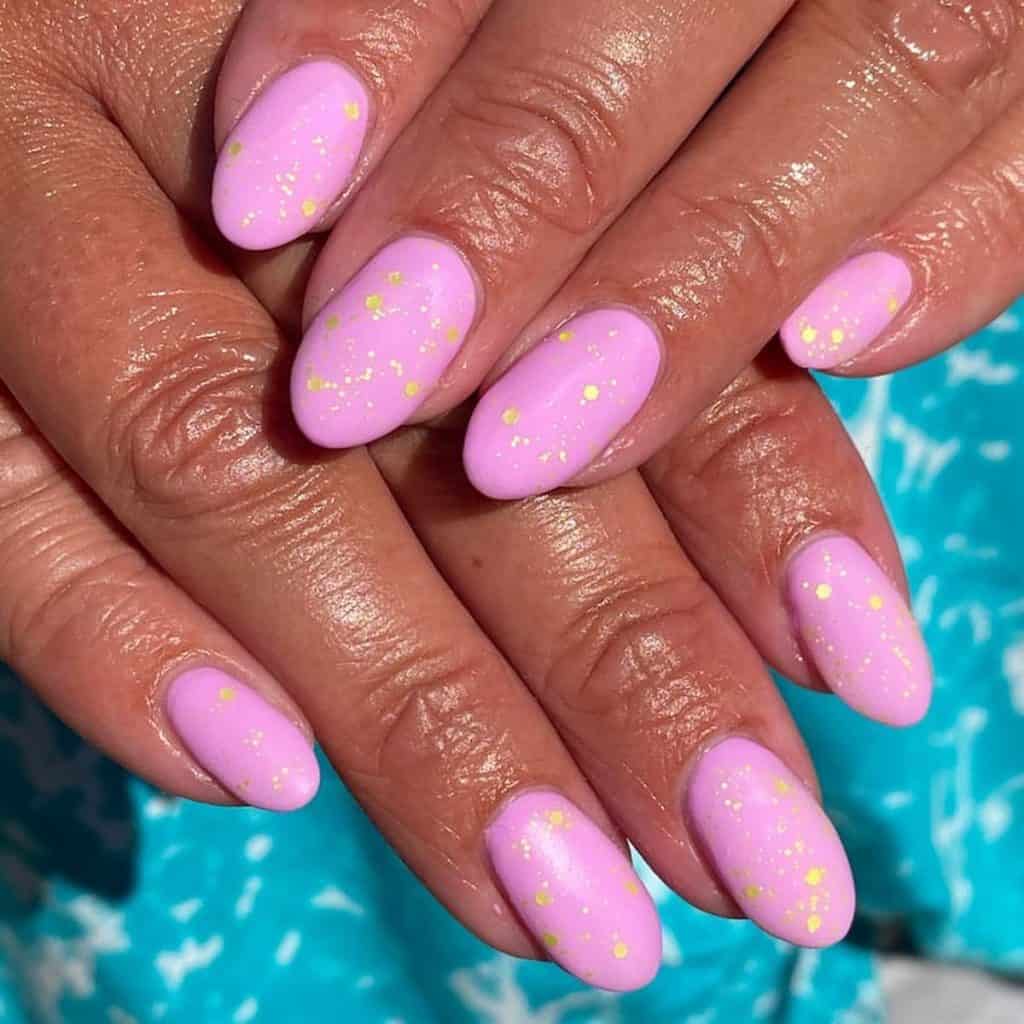 A woman's light pink matte nails are sprinkled with gold glitter