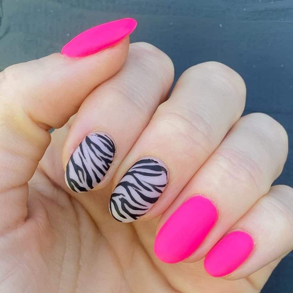 A woman's matte display with neon pink nails paired with accent nails decked in bold zebra print
