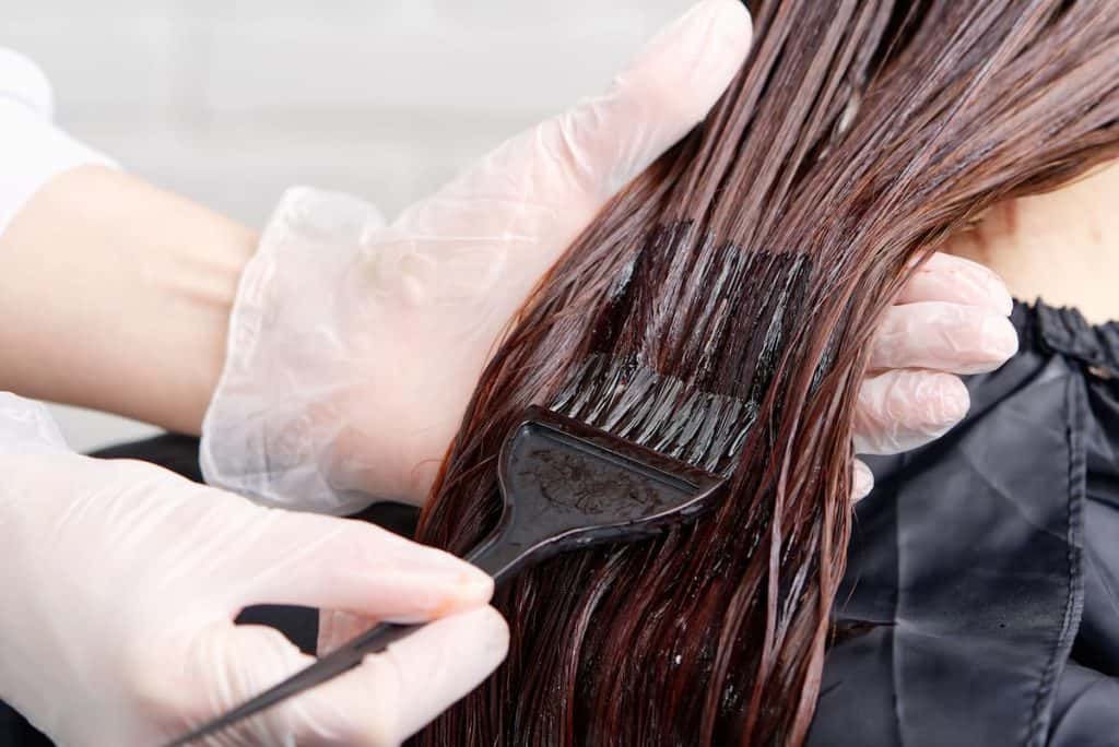 A woman is getting her hair dyed in a salon.