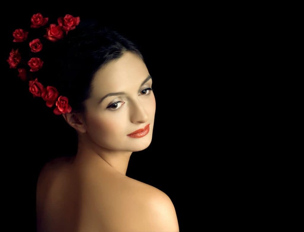 A beautiful woman with red roses in her hair.