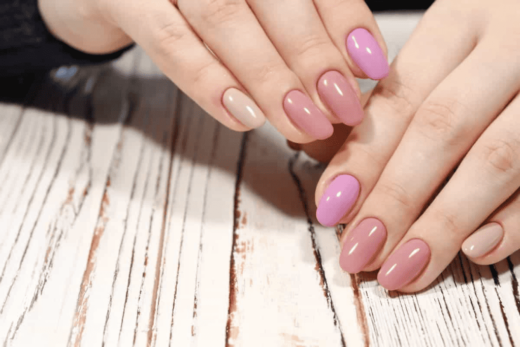 A woman with pink and purple nails on a wooden table.