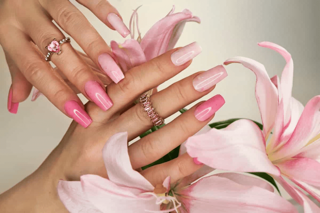 A woman's hands with pink nails and lilies.