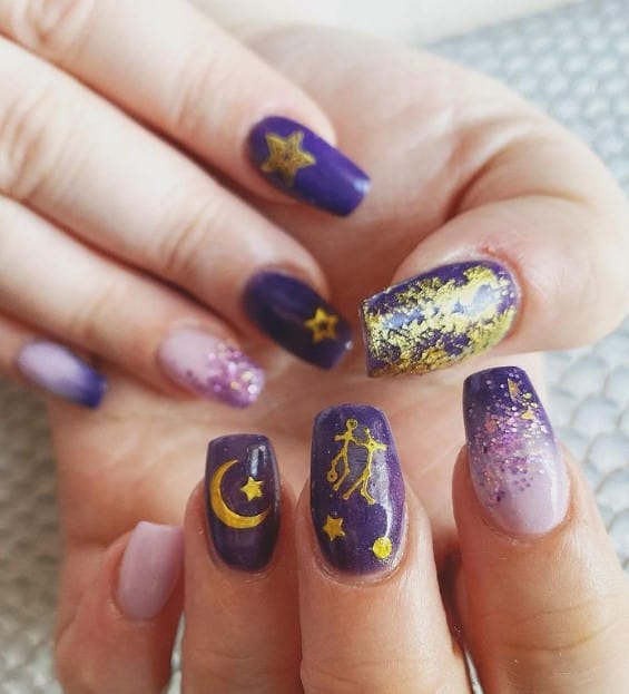 Embark on a celestial journey with nails in purple decorated with gold foil and gold-colored moons, stars, and constellations.
