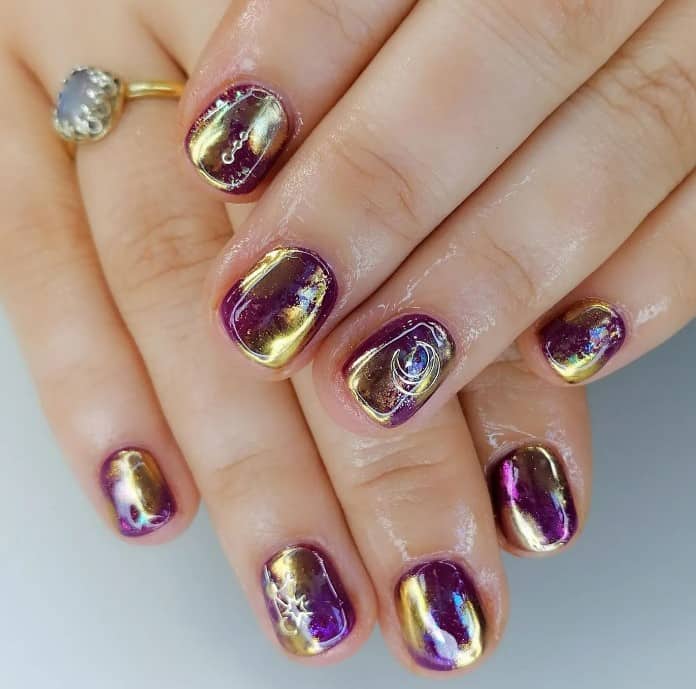 Chrome purple polish with swirls of gold brings the beauty of the galaxy to your short nails, along with the subtle crescent moon and star accents that add otherworldly elegance.