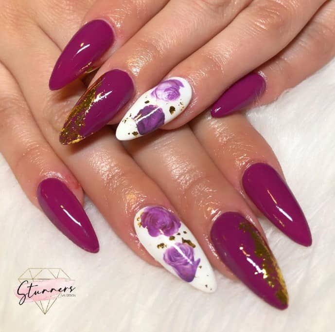 Long, sharp nails in magenta with smears of gold pair beautifully with pristine white nails adorned with gold foil and purple roses