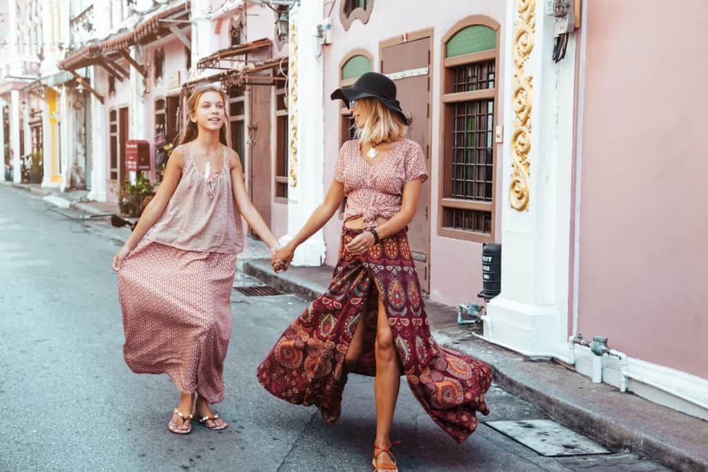 Boho mom with daughter in maxi skirt walking on the city street.