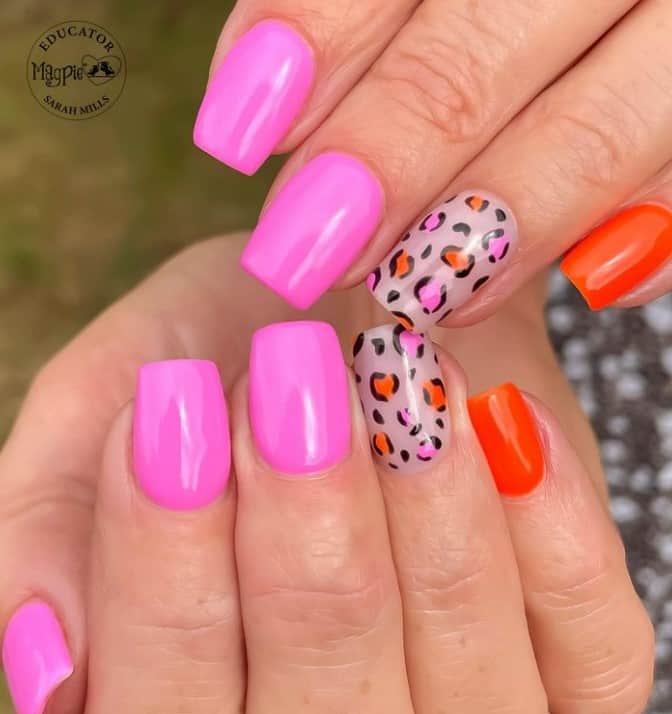 Vibrant pink nails make a splash next to leopard accents and a punchy orange nail, creating a wild and vivid manicure full of personality.