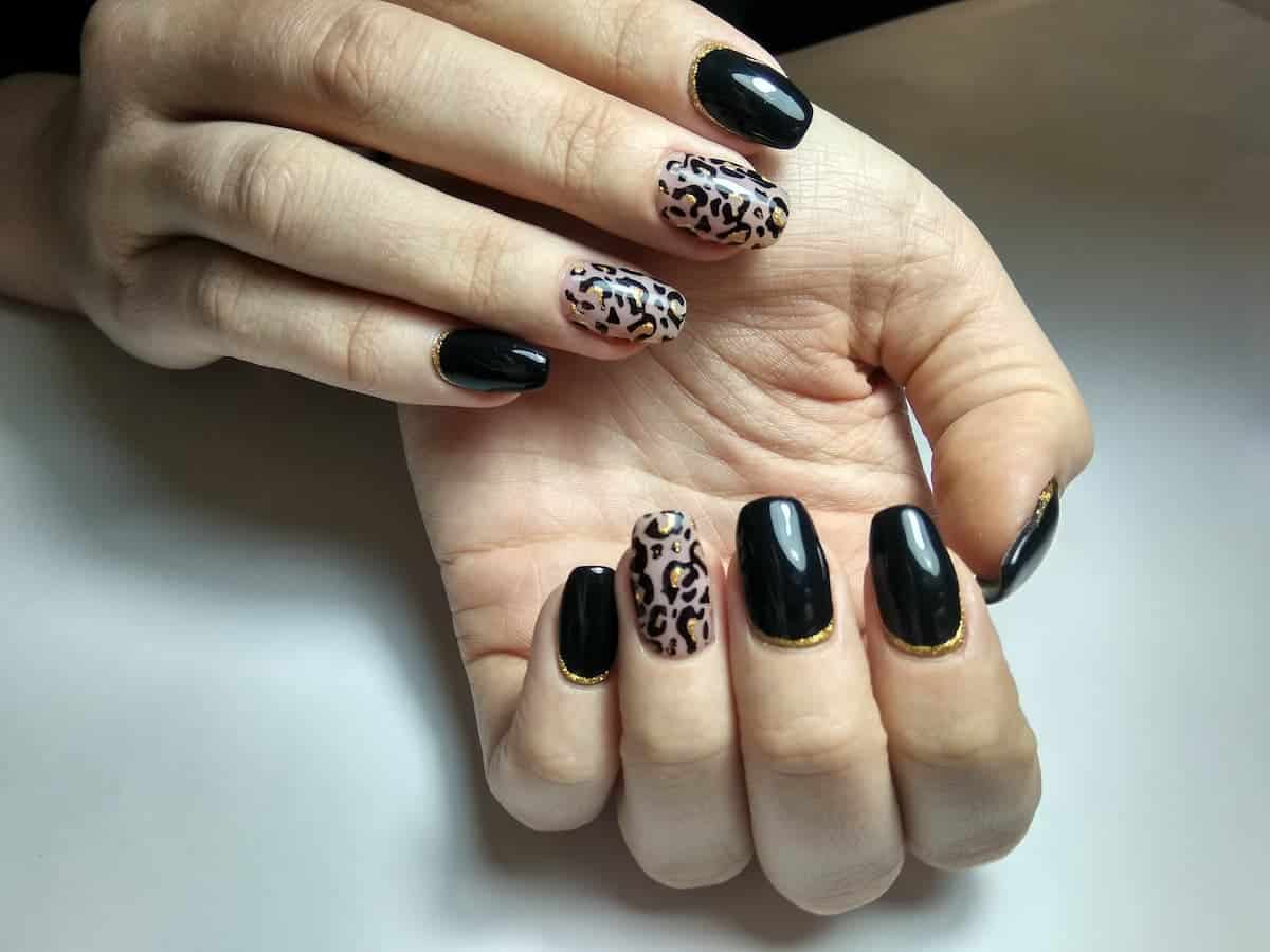 A woman's hands with black and leopard print nails.