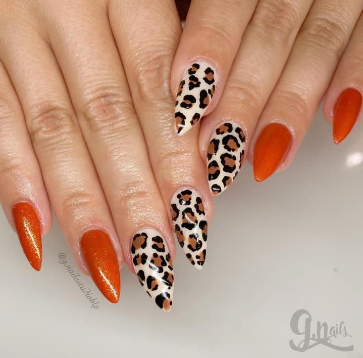 Glittery pumpkin orange pairs with a wild leopard print in this mani, creating a fierce and fiery almond-shaped nail design. 