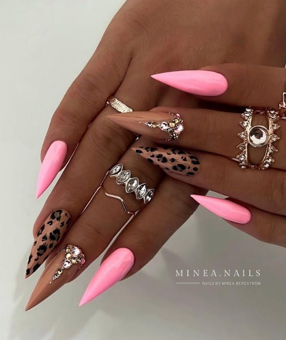 A hand with pink nails and rings.