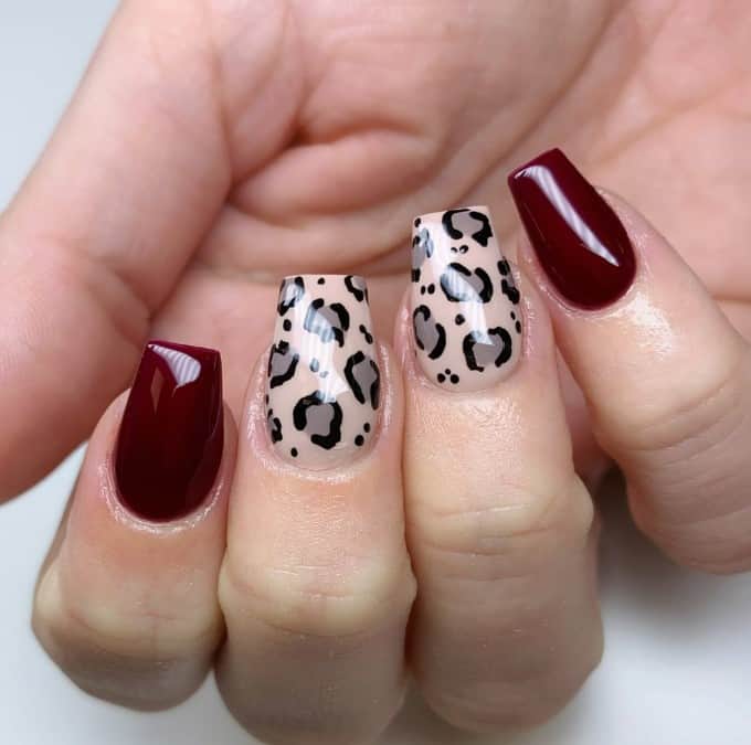 These burgundy nails lend a touch of deep elegance as leopard prints on a creamy base showcase a timeless yet playful nail design on two middle nails.