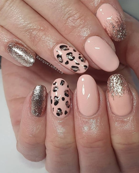 One nail is covered in radiant rose gold glitter, while another features leopard print with rose gold glittered centers. A third nail winks with a gradient of rose gold glitter at the tip, blending into the pink.