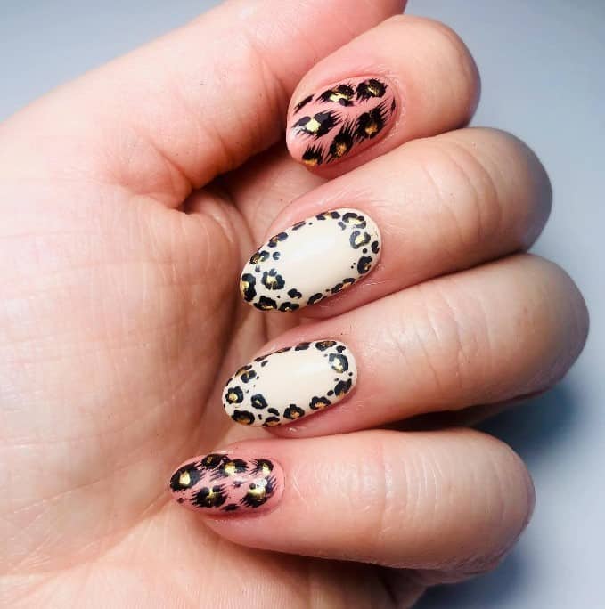 Unleash a playful edge with off-white nails that feature a border of bold black leopard spots, each highlighted by a touch of gold. 